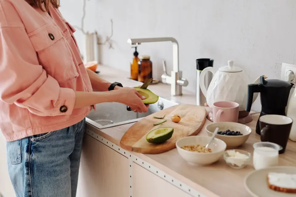 A dog looking up at an avocado sitting on a kitchen counter