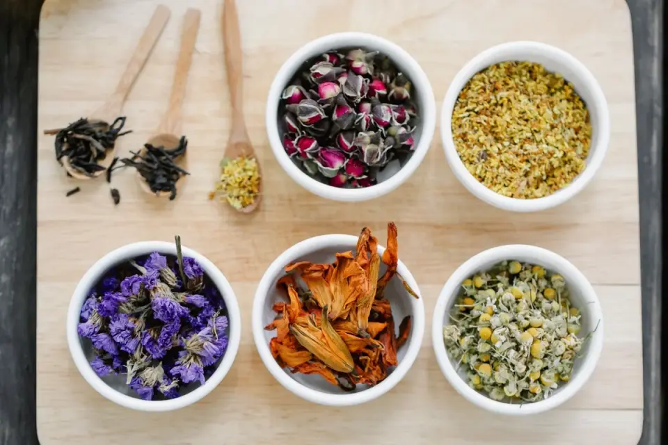 Dried chamomile flowers next to a small pile of soft dog chews on a wooden table